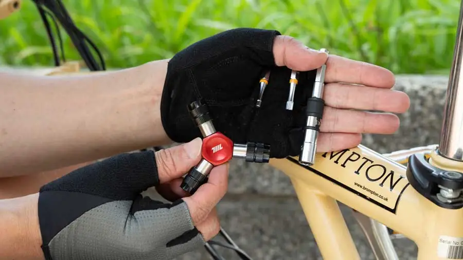 EDC-Fahrradwerkzeugkit – Hand hält 711L Y-Schraubendreher und Bit-Einsätze am Fahrradrahmen